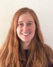 An image of Annika Muelhbradt, a young woman with long red hair and a maroon shirt.