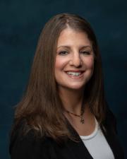 Robin Troutman, a smiling middle-aged woman with long straight brown hair, a black suit jacket and white shirt